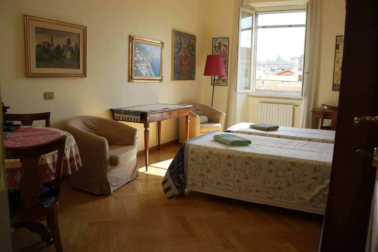 La camera con i letti, la finestra e il sole sul parquet